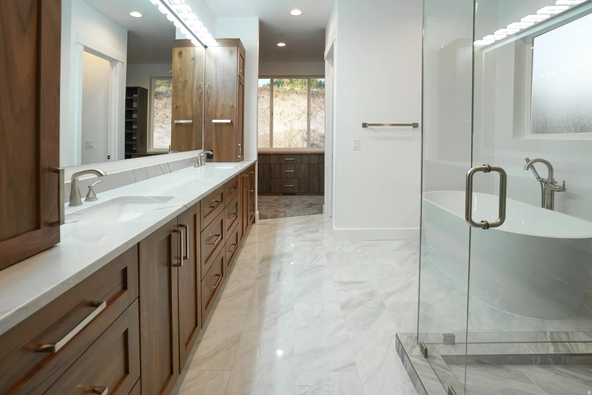 Bathroom with double vanity, a freestanding bath, recessed lighting, and a shower stall