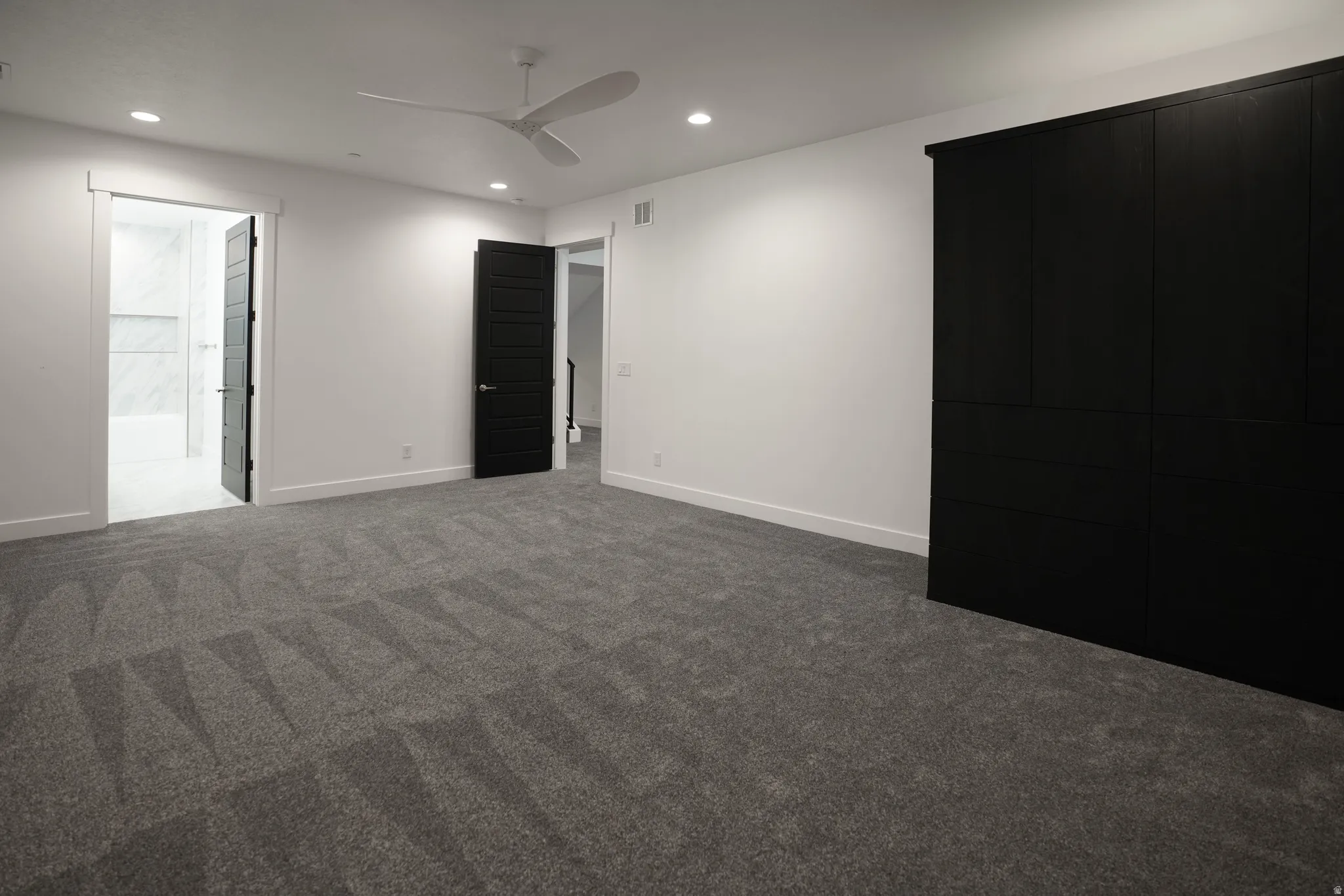 Unfurnished bedroom featuring a ceiling fan, recessed lighting, dark carpet, and ensuite bathroom
