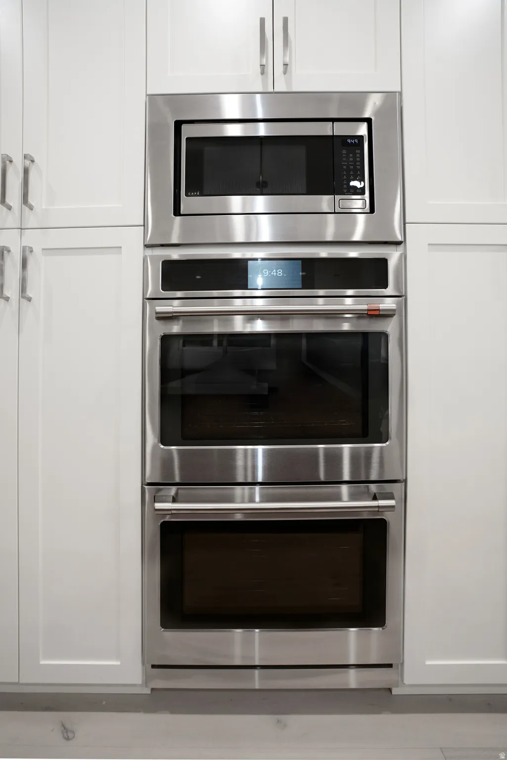 Kitchen view of stainless steel appliances and white cabinets