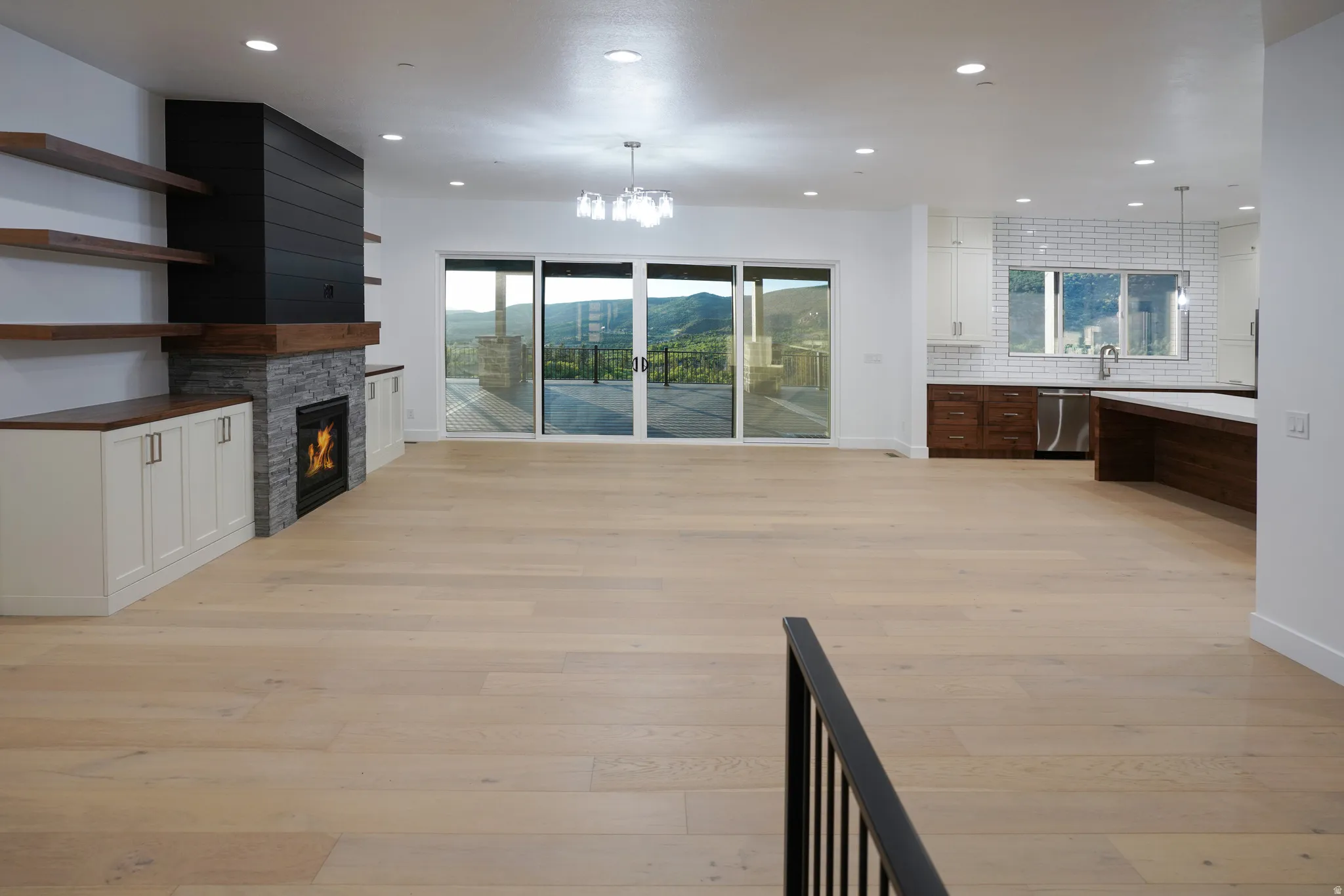 Unfurnished living room featuring light wood-style floors, a stone fireplace, hanging lights, and a mountain view