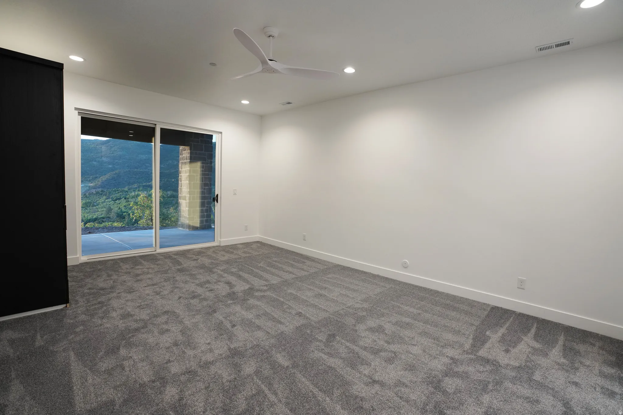 Empty room with a ceiling fan, dark carpet, and recessed lighting