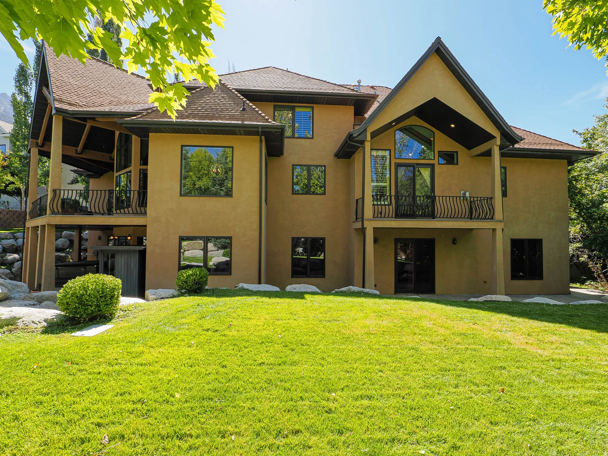 Back of property featuring a balcony, stucco siding, and a lawn