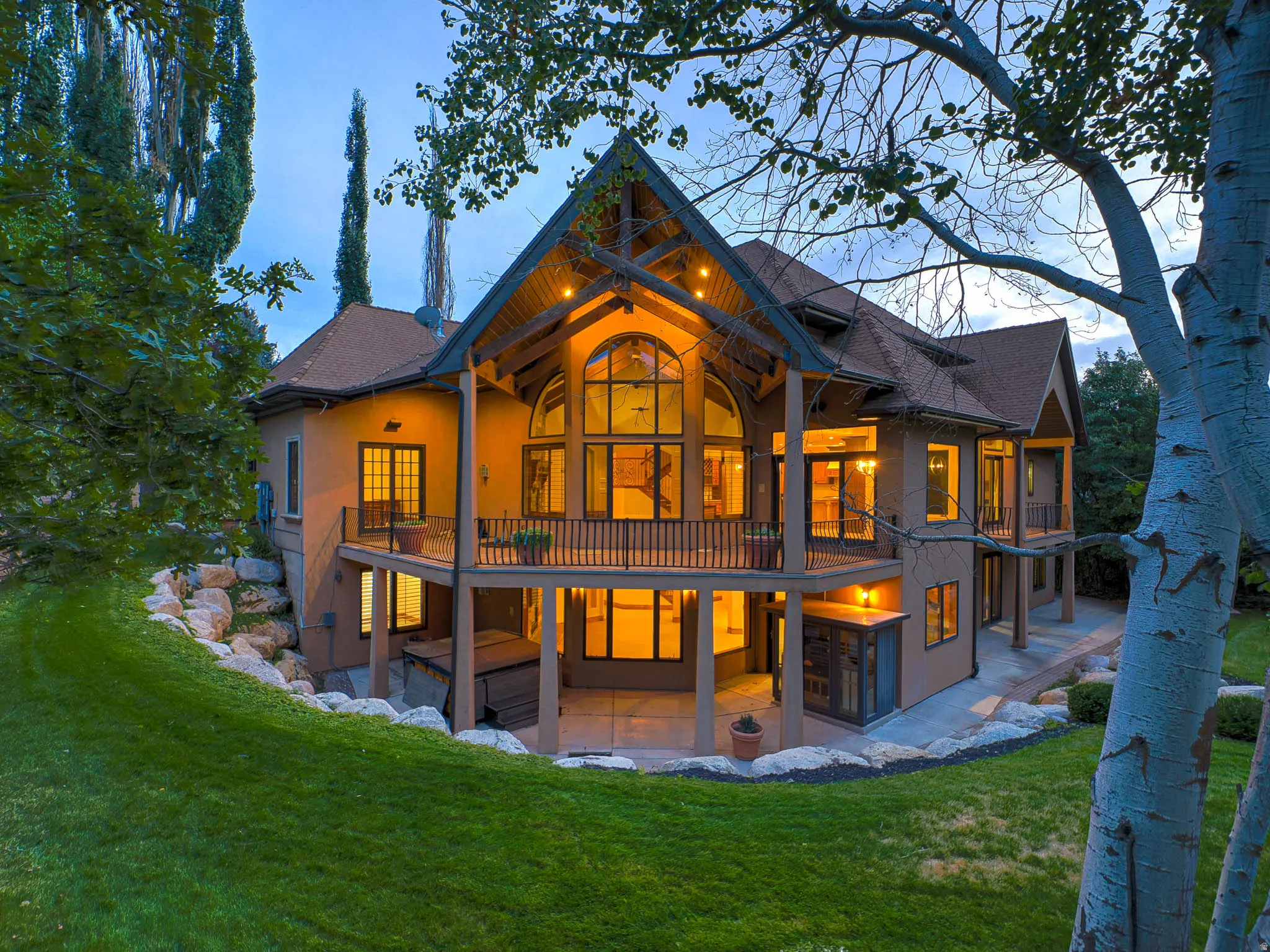Rear view of property featuring a patio area, stucco siding, a lawn, and a balcony