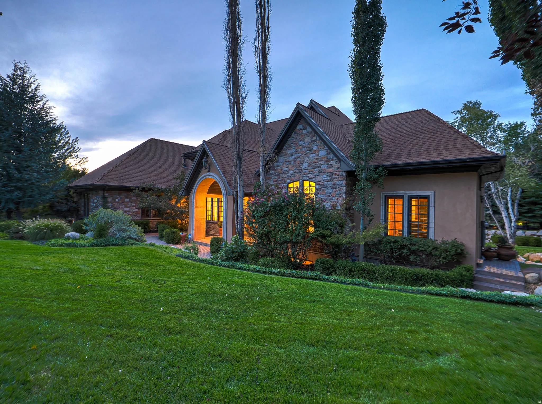 View of front of home featuring a lawn, stone siding, and stucco siding