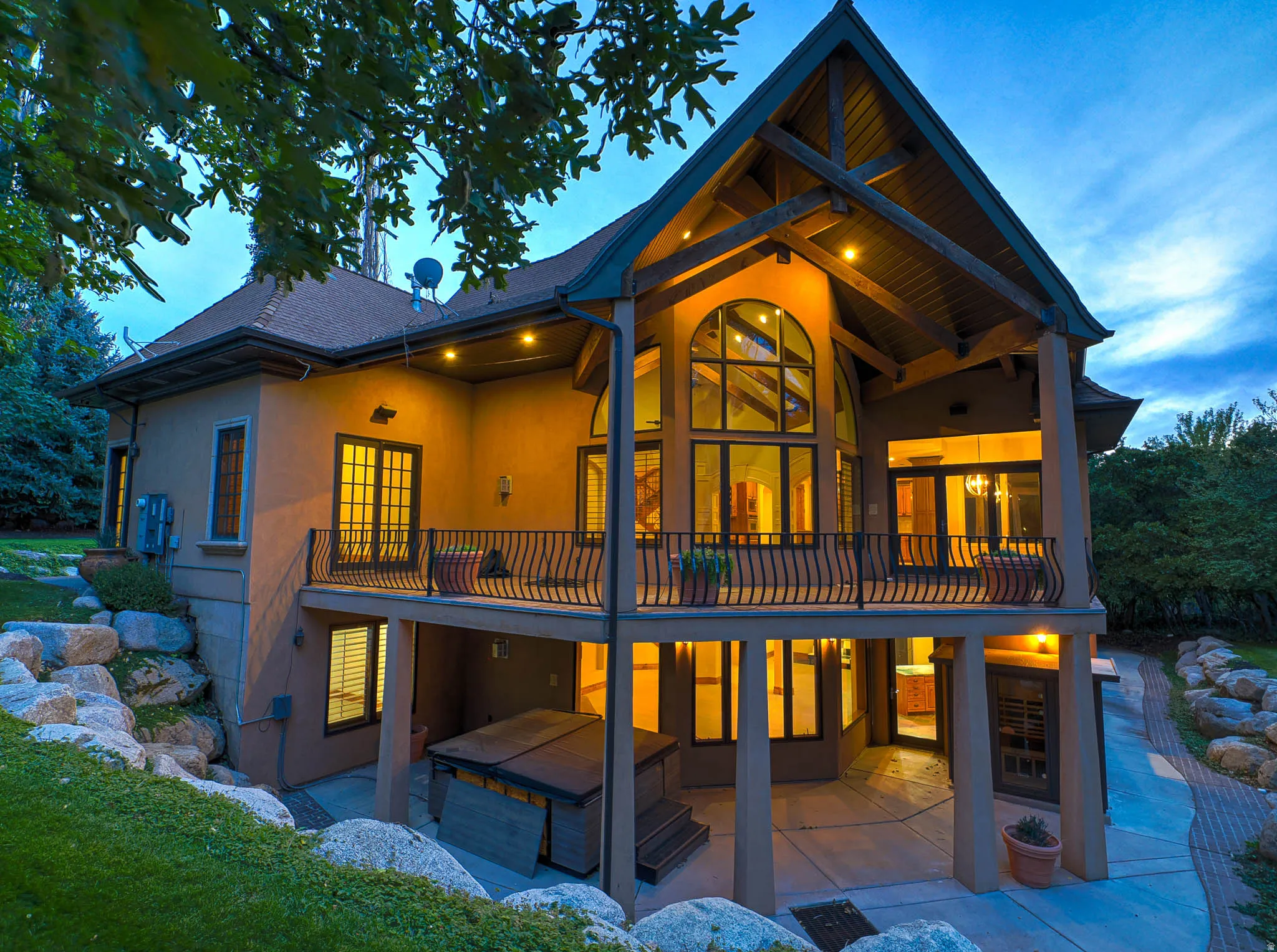 Back of house at dusk with a patio, a shingled roof, and stucco siding