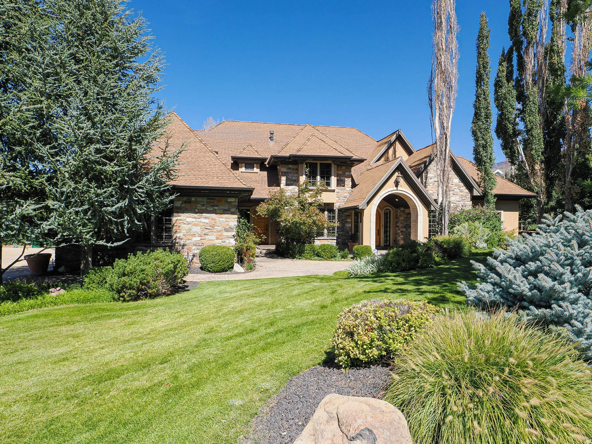 View of front of home featuring stone siding and a front yard