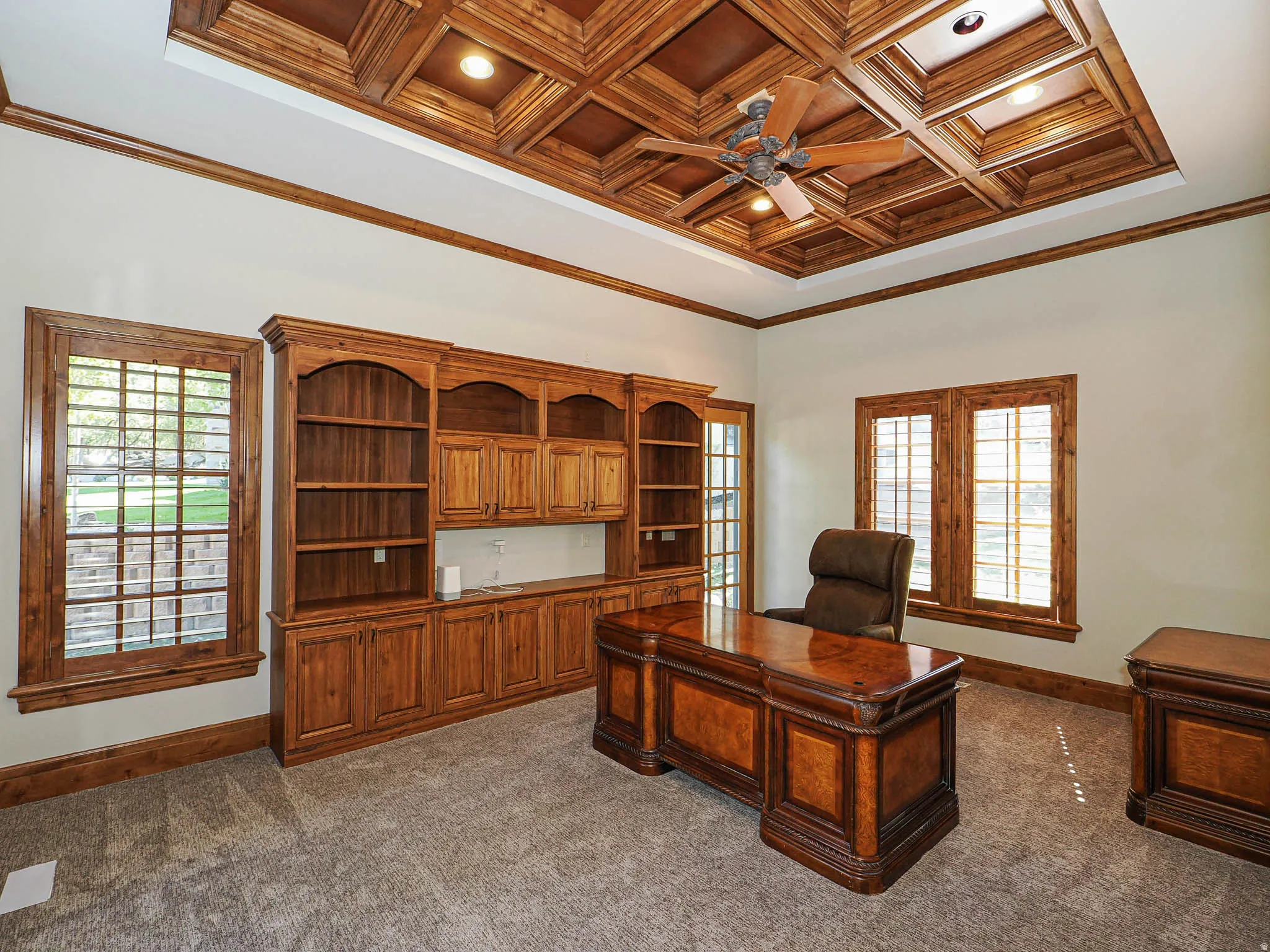 Office space with ornamental molding, ceiling fan, coffered ceiling, dark carpet, and recessed lighting