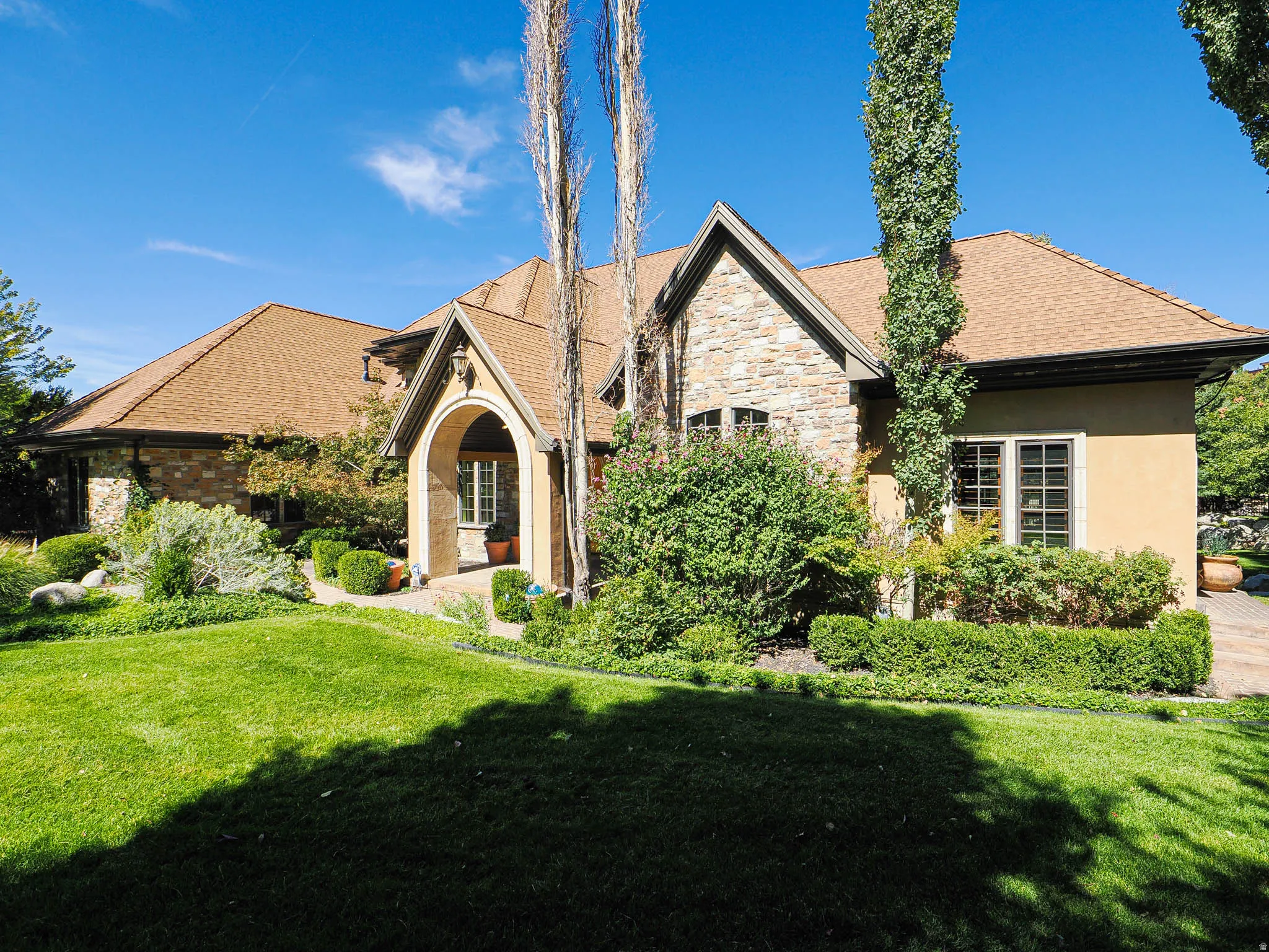 View of front of home featuring a front lawn, stone siding, and stucco siding