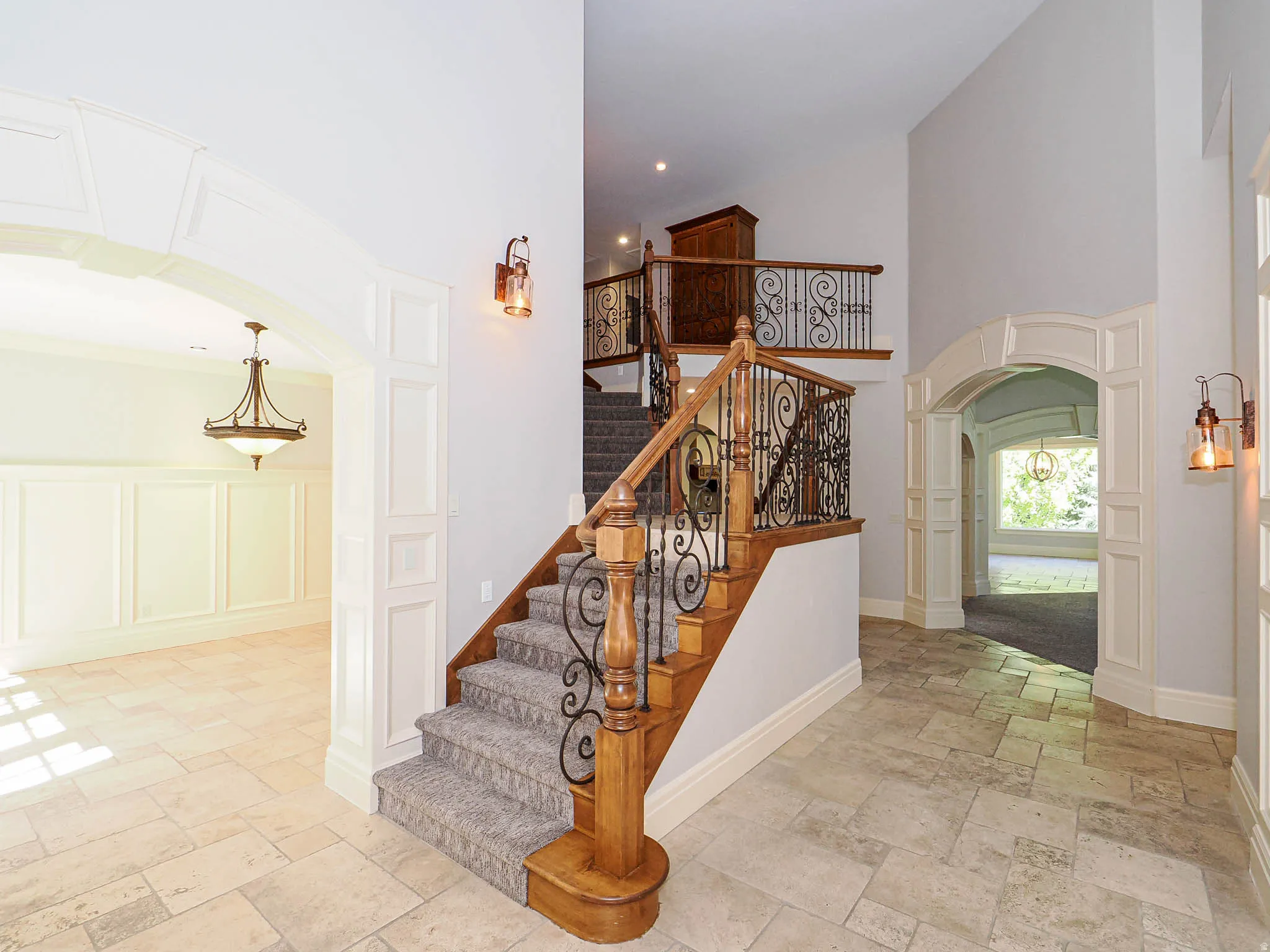 Stairs featuring arched walkways, a high ceiling, stone tile floors, decorative columns, and a decorative wall