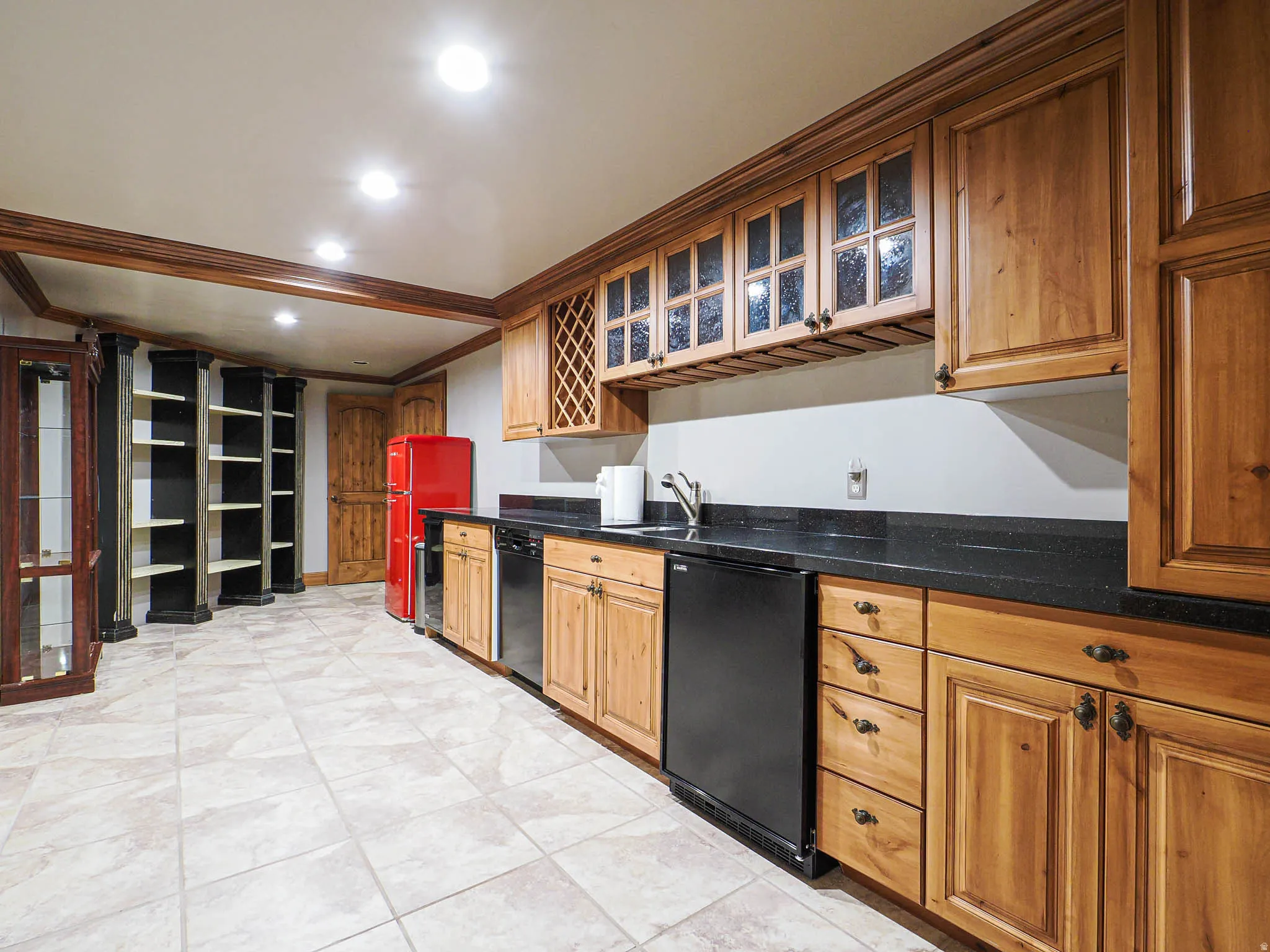 Kitchen with glass insert cabinets, ornamental molding, recessed lighting, freestanding refrigerator, and dark stone counters