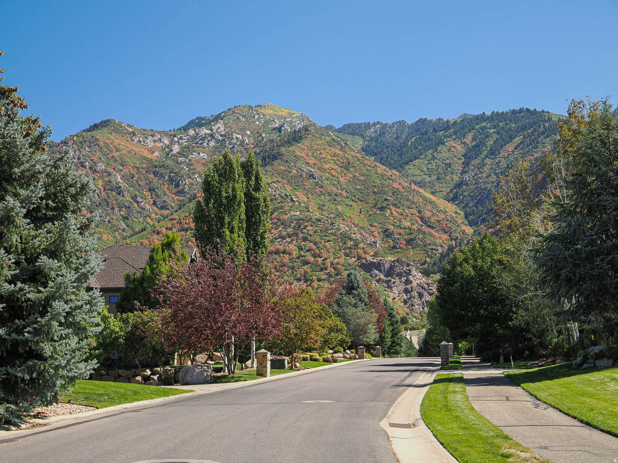 View of asphalt street with sidewalks, a mountain view, and curbs