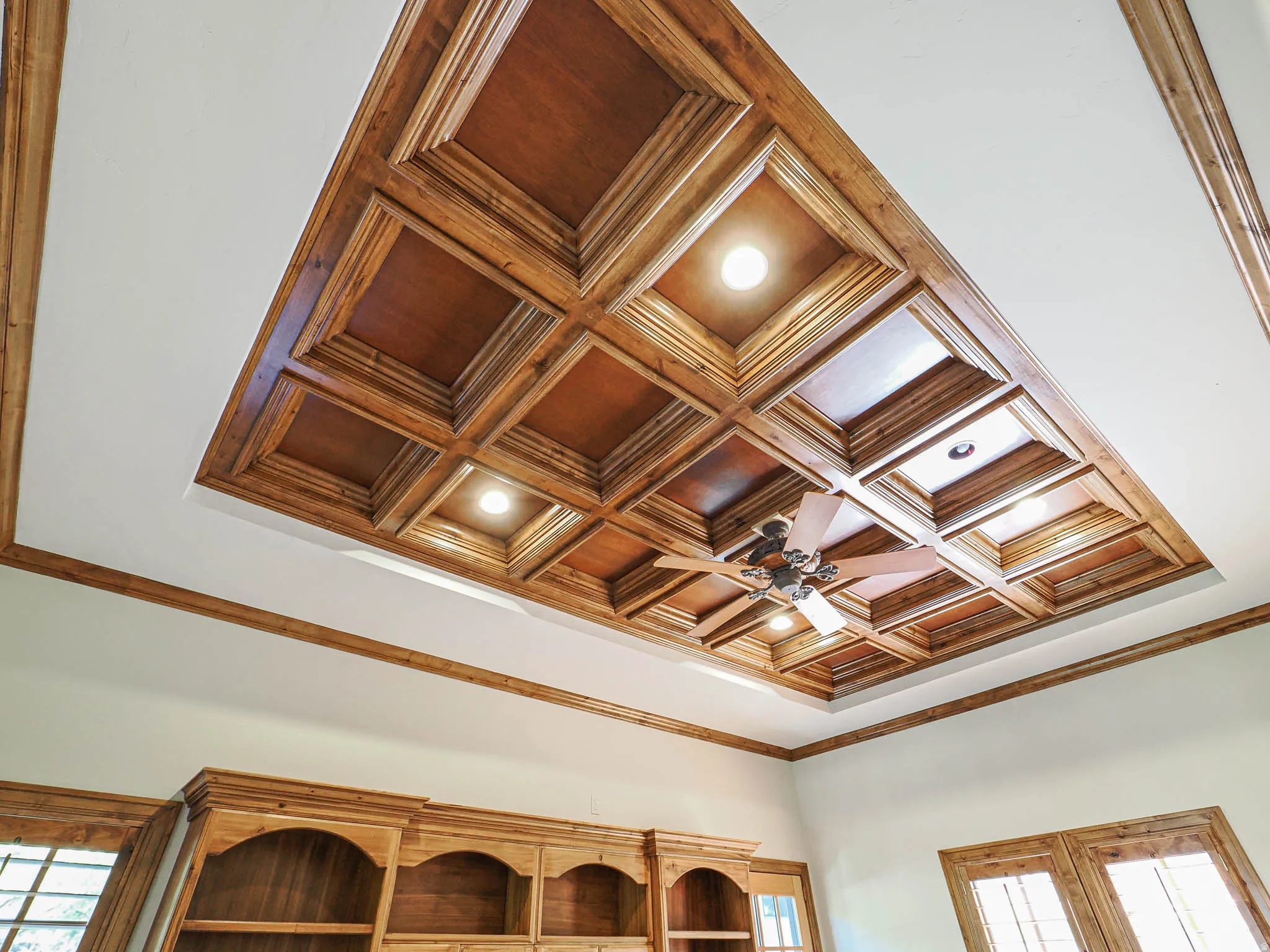 Detailed view of crown molding, coffered ceiling, and ceiling fan