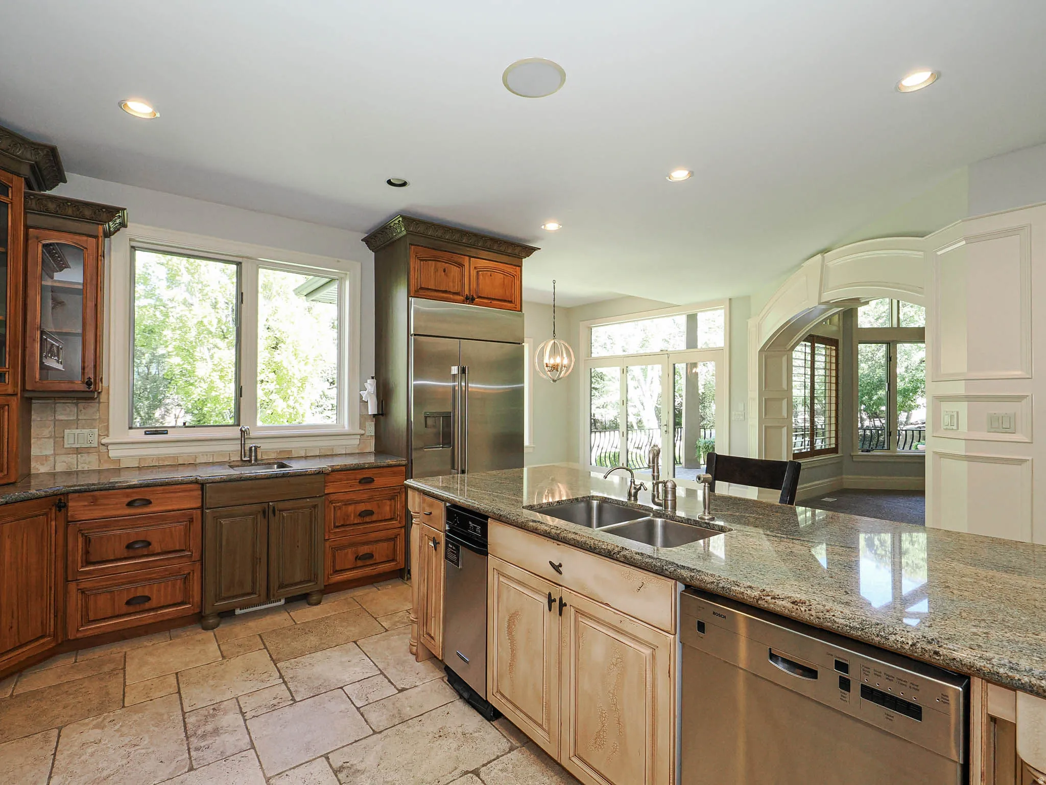 Kitchen featuring stainless steel appliances, dark stone countertops, glass insert cabinets, stone tile floors, and healthy amount of natural light