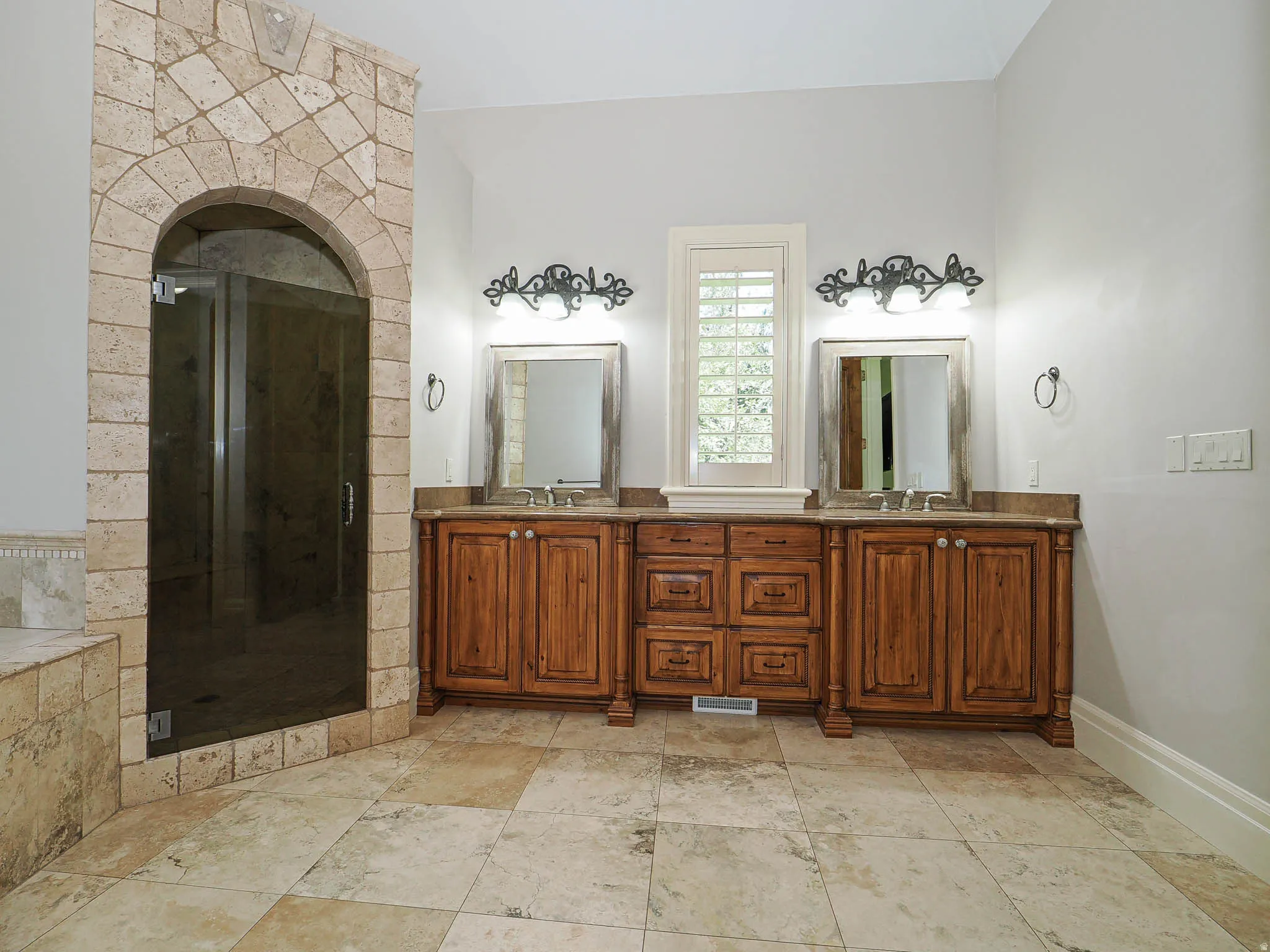 Full bathroom with double vanity, a shower stall, a garden tub, and stone tile floors