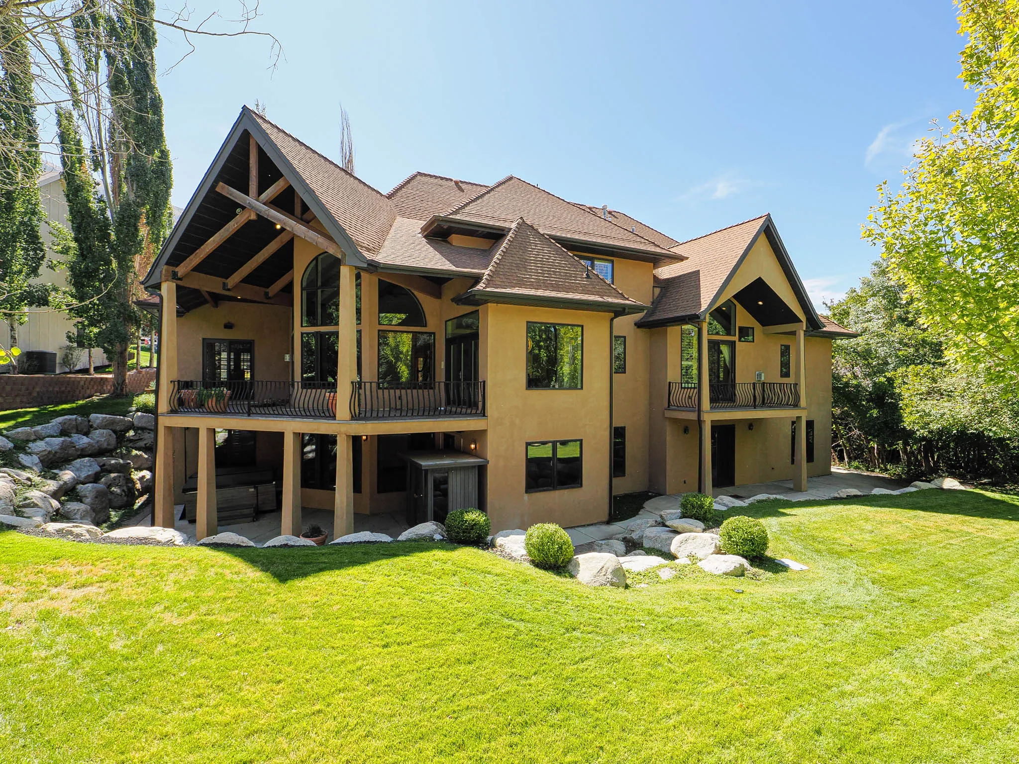 Rear view of house featuring a yard, a shingled roof, stucco siding, and a patio