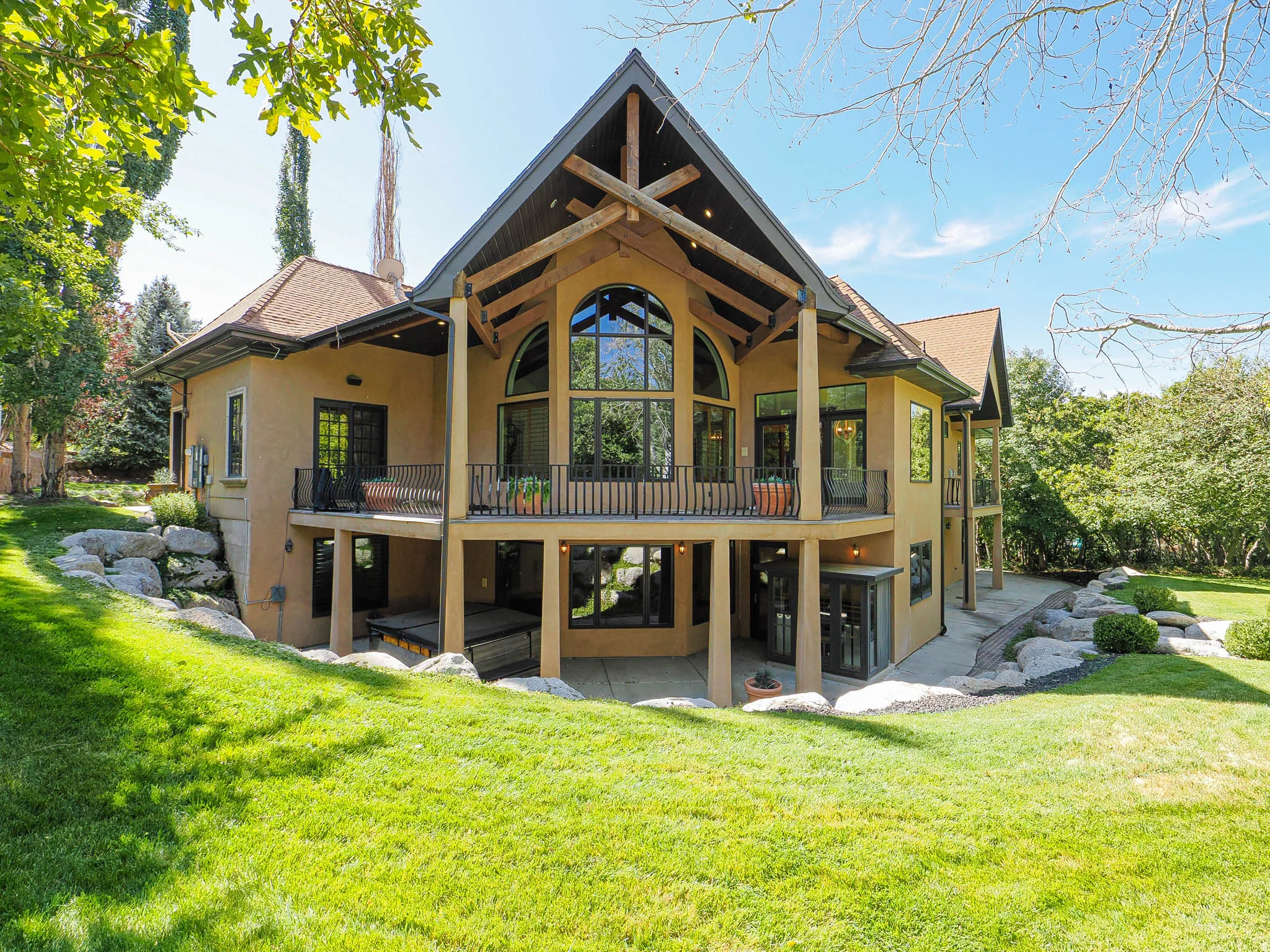 Back of house with stucco siding, a patio area, a balcony, and a yard