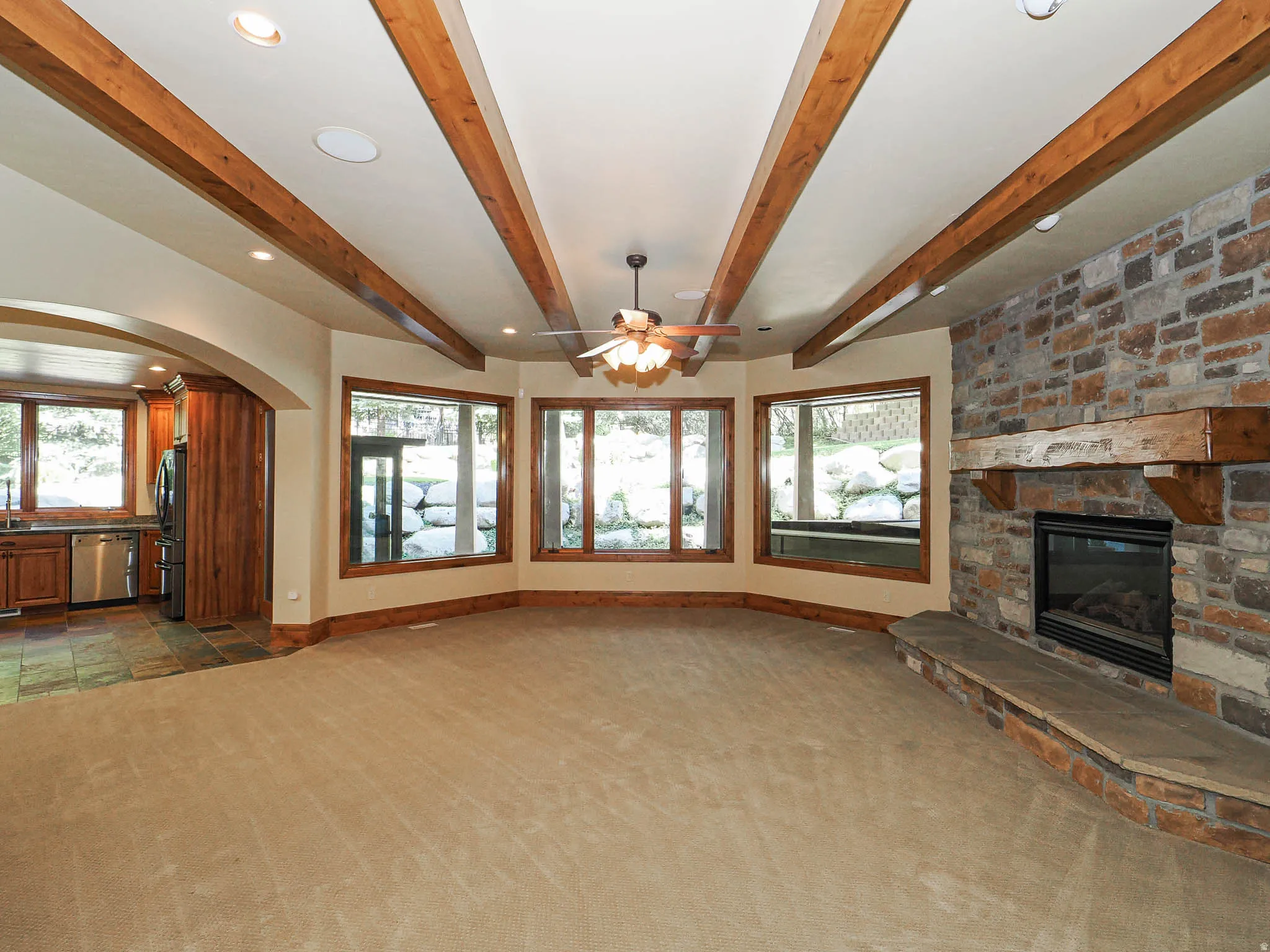 Unfurnished living room featuring a fireplace, healthy amount of natural light, carpet floors, recessed lighting, and beamed ceiling