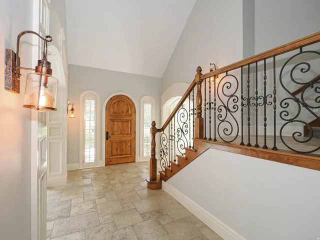 Foyer with lofted ceiling, stone tile flooring, and arched doorway