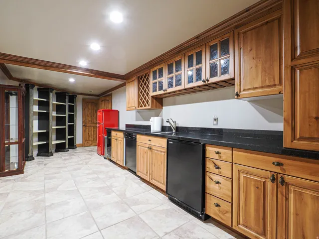 Kitchen with glass insert cabinets, ornamental molding, recessed lighting, freestanding refrigerator, and dark stone counters