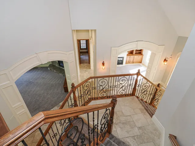 Staircase with a high ceiling, arched walkways, stone finish floors, and carpet floors