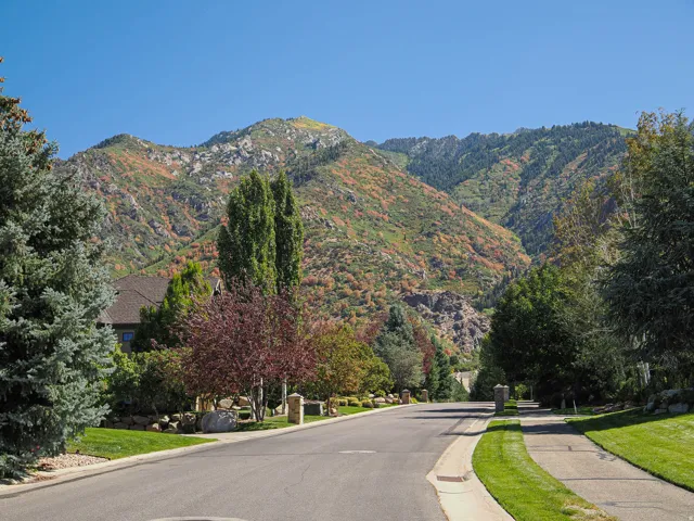 View of asphalt street with sidewalks, a mountain view, and curbs
