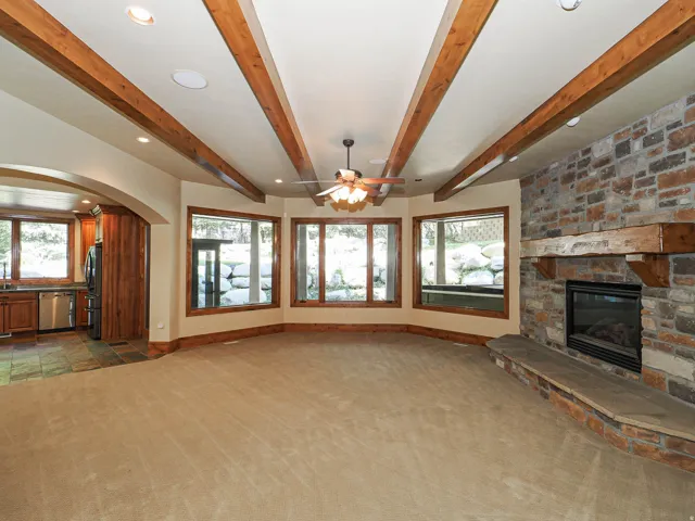 Unfurnished living room featuring a fireplace, healthy amount of natural light, carpet floors, recessed lighting, and beamed ceiling