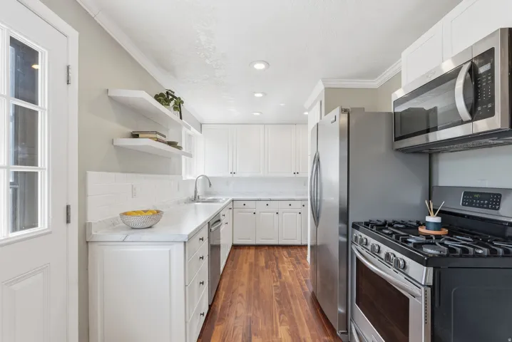 Modern kitchen featuring white cabinetry, light countertops, wood-finish flooring, stainless steel appliances, and recessed lighting