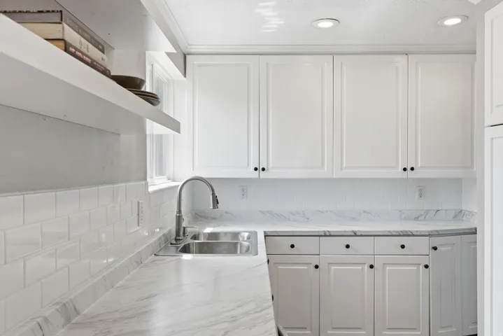 Kitchen featuring light-toned cabinetry with dark hardware, a stainless steel double-basin sink, and a pull-down faucet