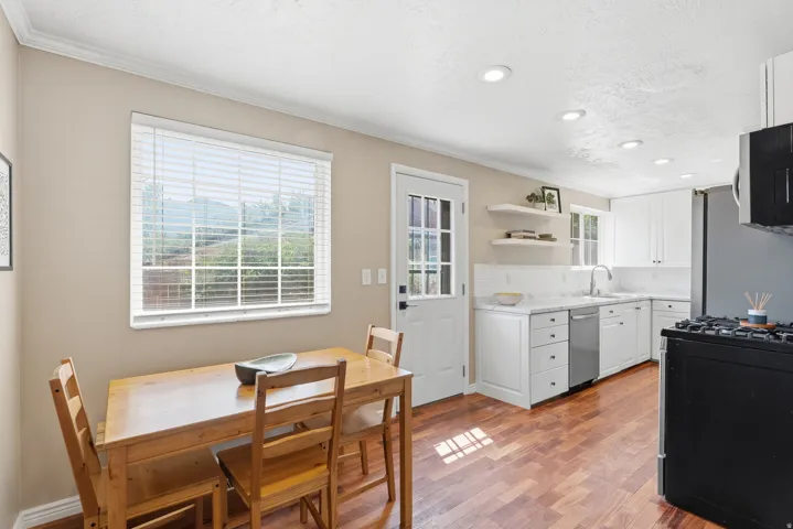 Kitchen featuring wood-finish flooring, white cabinetry, integrated stainless steel dishwasher, white countertop, and recessed lighting