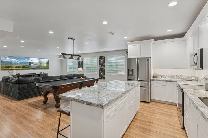 Kitchen featuring stainless steel appliances, light stone counters, a kitchen breakfast bar, a kitchen island, and white cabinets