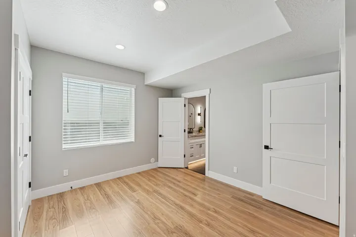 Unfurnished bedroom featuring light wood-style floors, ensuite bathroom, a textured ceiling, and recessed lighting