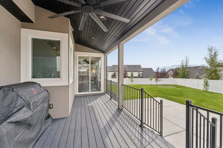 Wooden terrace with ceiling fan, area for grilling, and a residential view