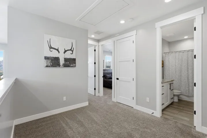 Hallway with light colored carpet and attic access