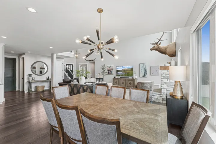 Spacious dining area featuring wood-finish flooring, a modern sputnik chandelier, and a stone-clad fireplace