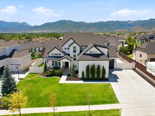 Contemporary style residence featuring a dark roof, white siding with black trim, a manicured lawn, and a wide concrete driveway