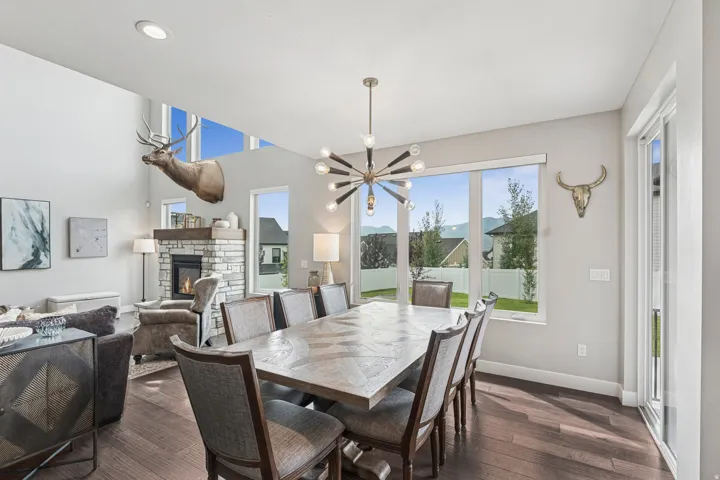 Open-concept dining area featuring wood-finish flooring, a contemporary chandelier, and large windows
