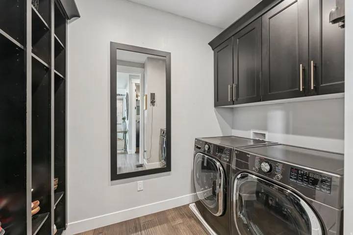Laundry room with cabinet space, dark wood-style flooring, and washing machine and clothes dryer