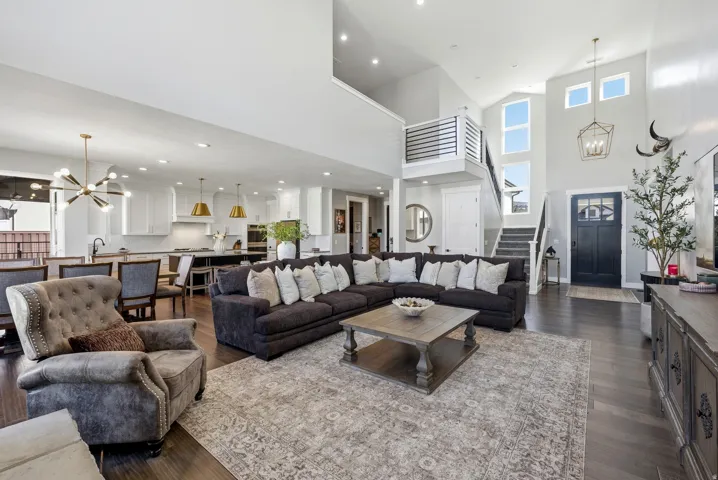 Open-concept interior featuring wood-finish flooring, a two-story entryway with multiple windows, and a staircase with metal railings