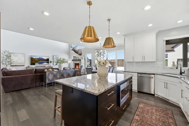 Open-concept kitchen featuring an island with a light-toned countertop, integrated microwave, and pendant lighting