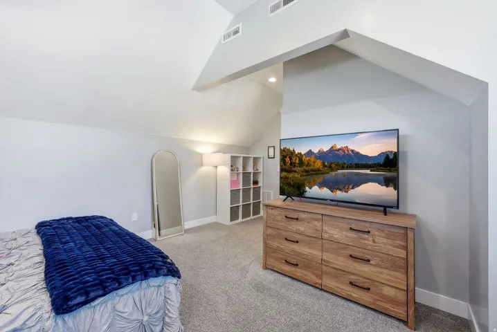 Bedroom featuring light carpet and lofted ceiling