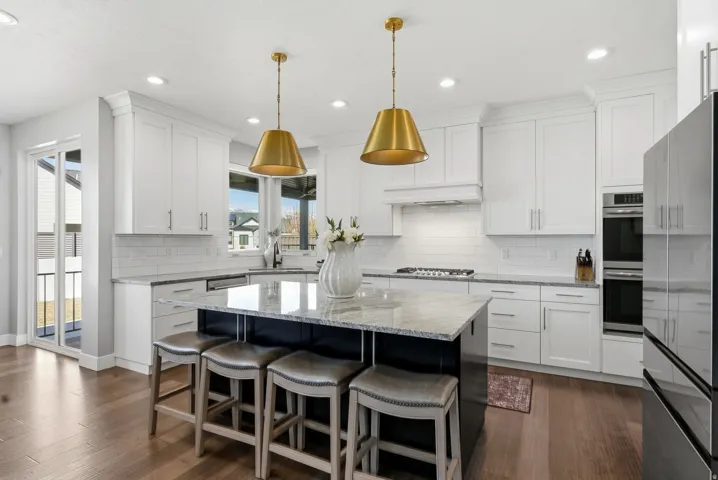 Dual tone kitchen with light stone counters, a kitchen breakfast bar, a center island, stainless steel appliances, and two tone cabinets