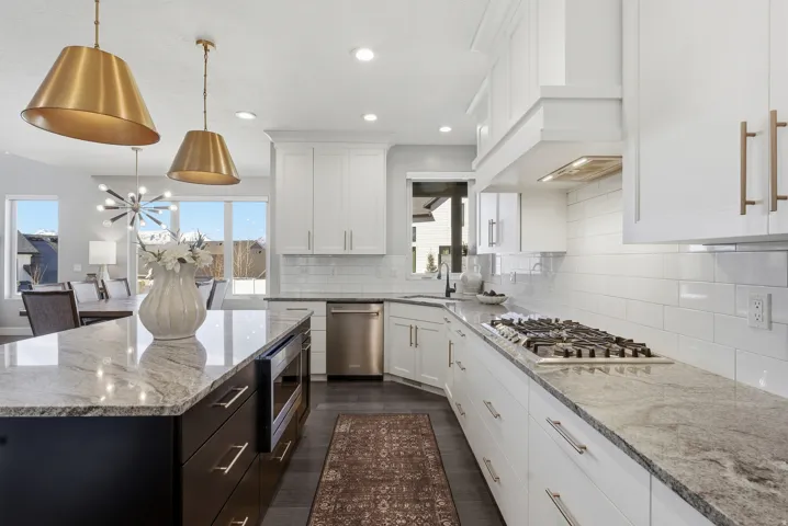 Spacious kitchen featuring an expansive island with an integrated microwave, white cabinetry, a gas cooktop, and stainless steel appliances