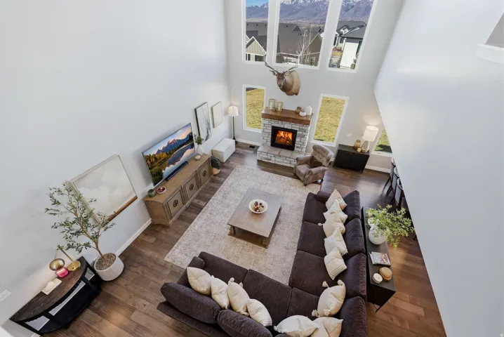 Living room with a high ceiling, dark wood-style flooring, and a stone fireplace