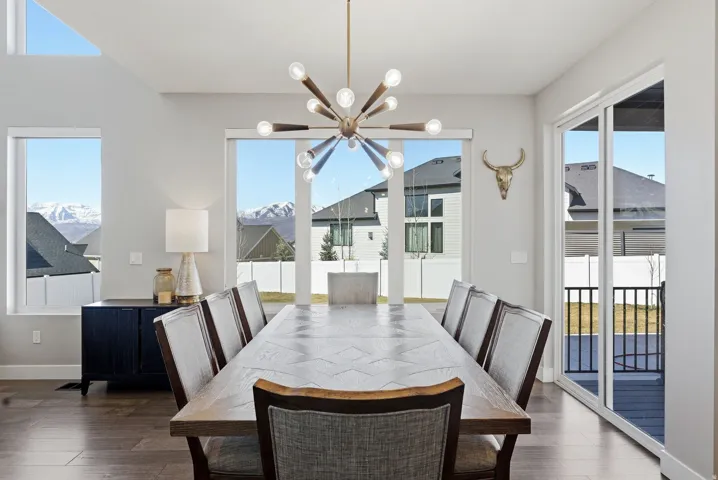 Dining area with a chandelier, plenty of natural light, and dark wood-style flooring