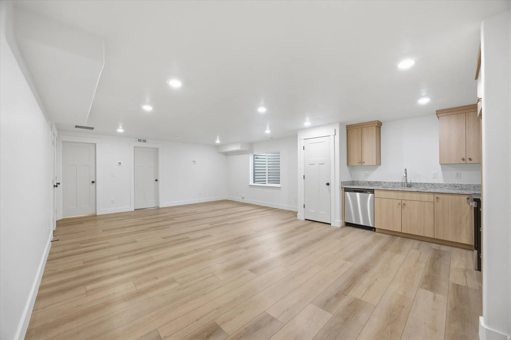 Kitchen with light wood finish cabinets, light wood finished floors, stainless steel appliances, recessed lighting, and light stone counters
