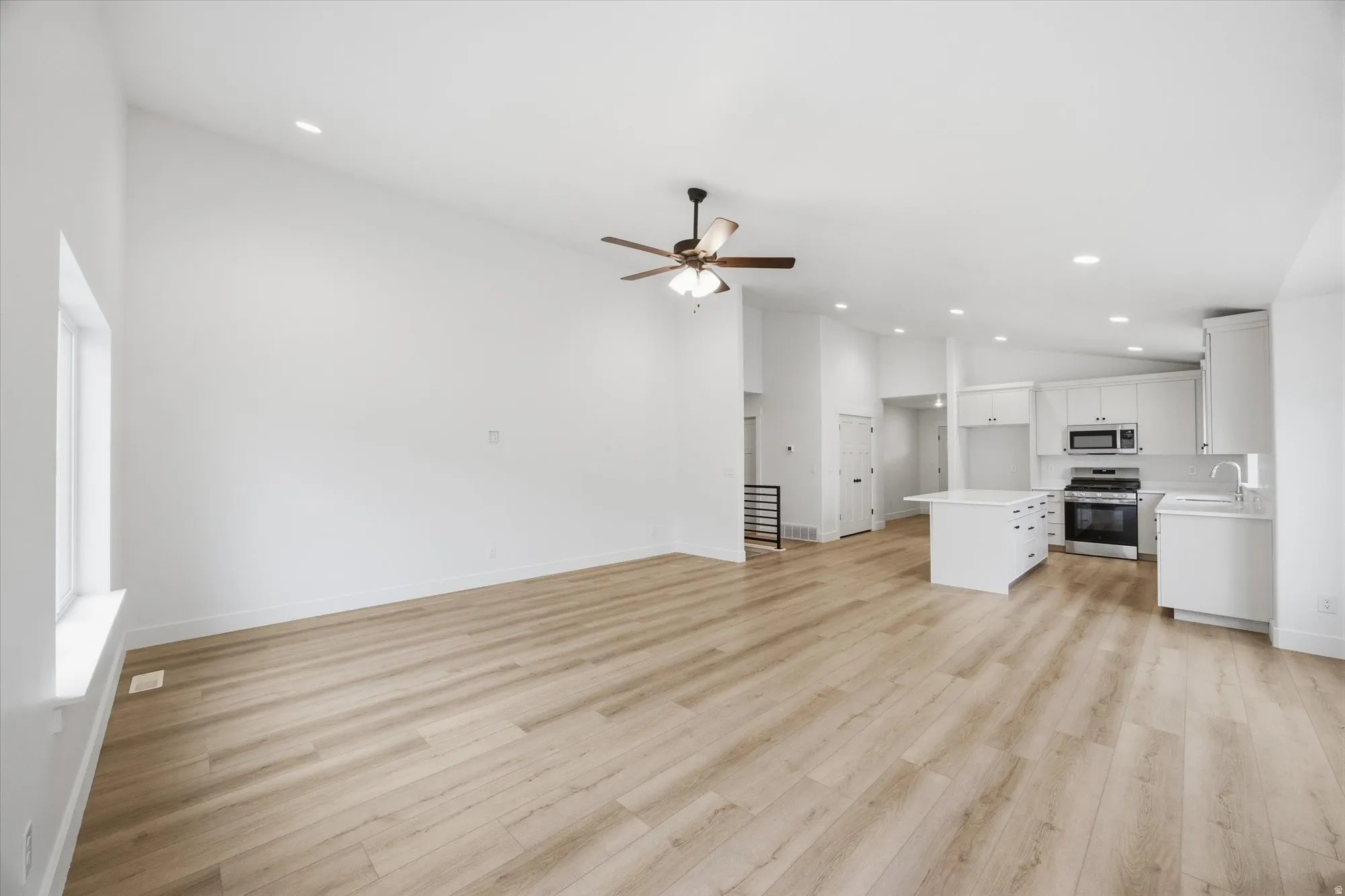 Unfurnished living room with recessed lighting, a ceiling fan, light wood finished floors, and vaulted ceiling