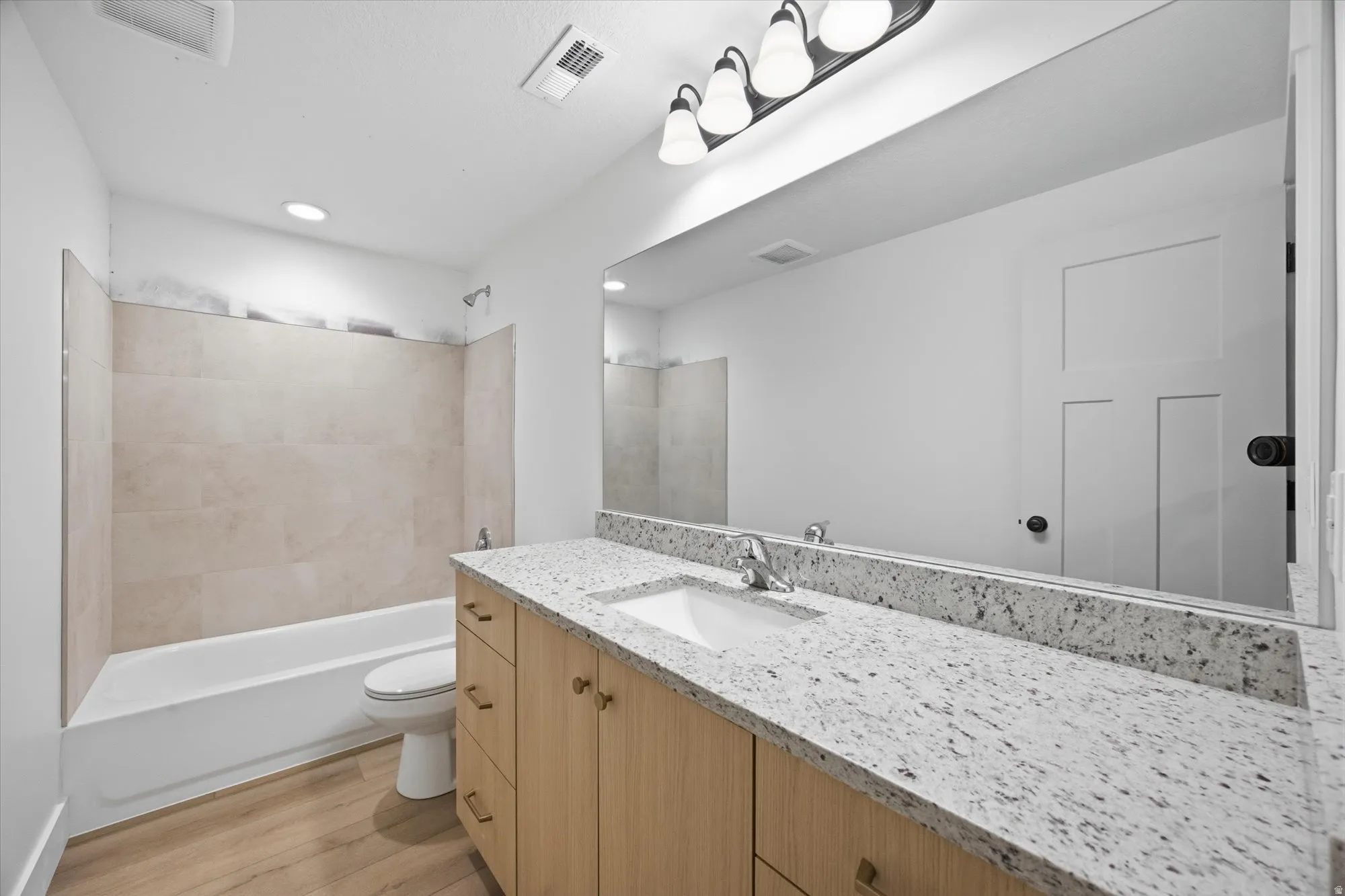 Bathroom with vanity, washtub / shower combination, and light wood-type flooring