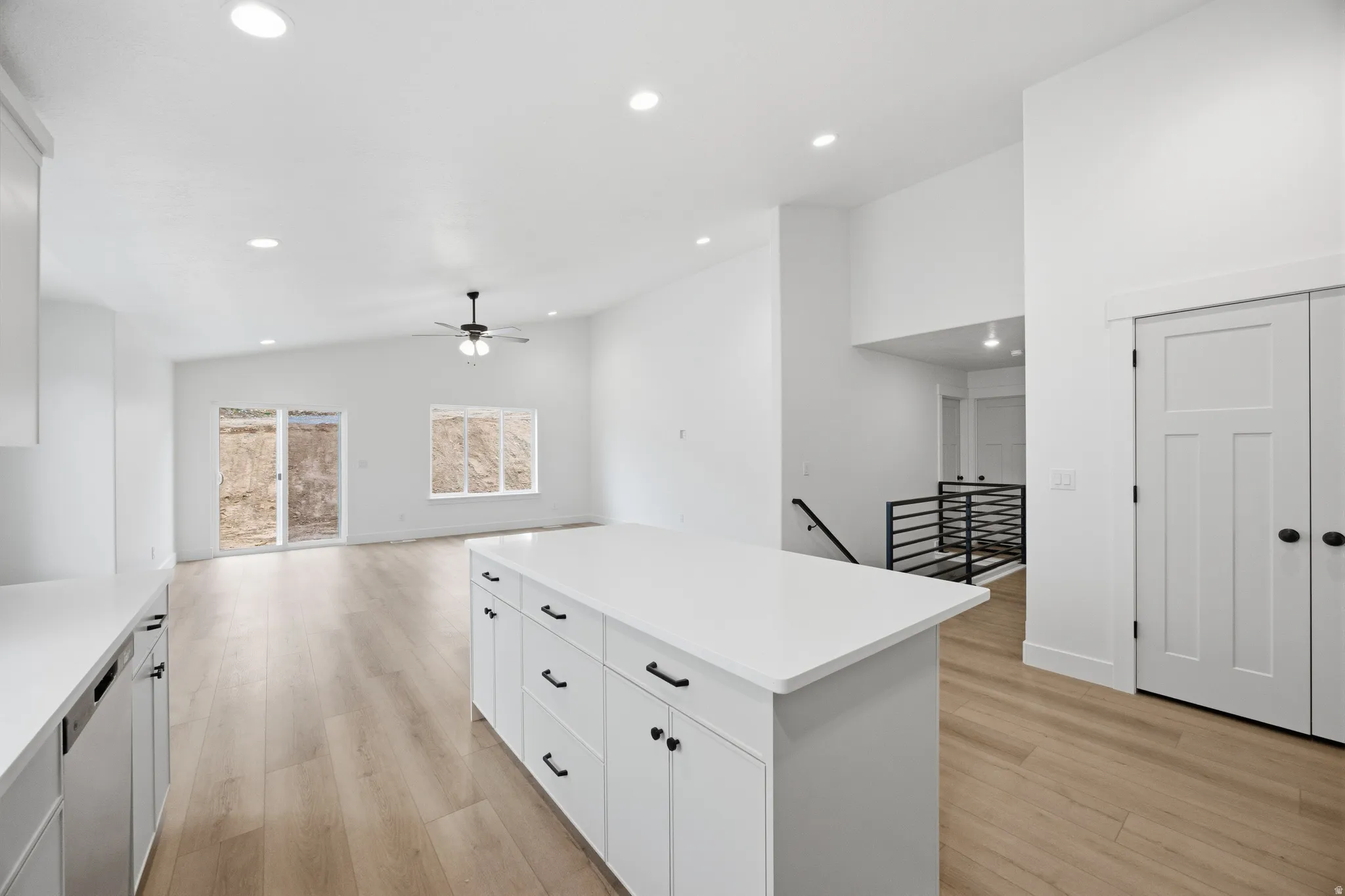 Kitchen with vaulted ceiling, a kitchen island, white cabinets, light wood finished floors, and recessed lighting