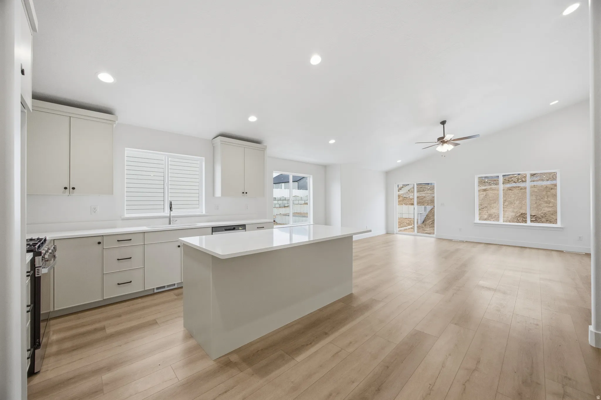Kitchen with recessed lighting, a kitchen island, light wood-style flooring, gas stove, and lofted ceiling