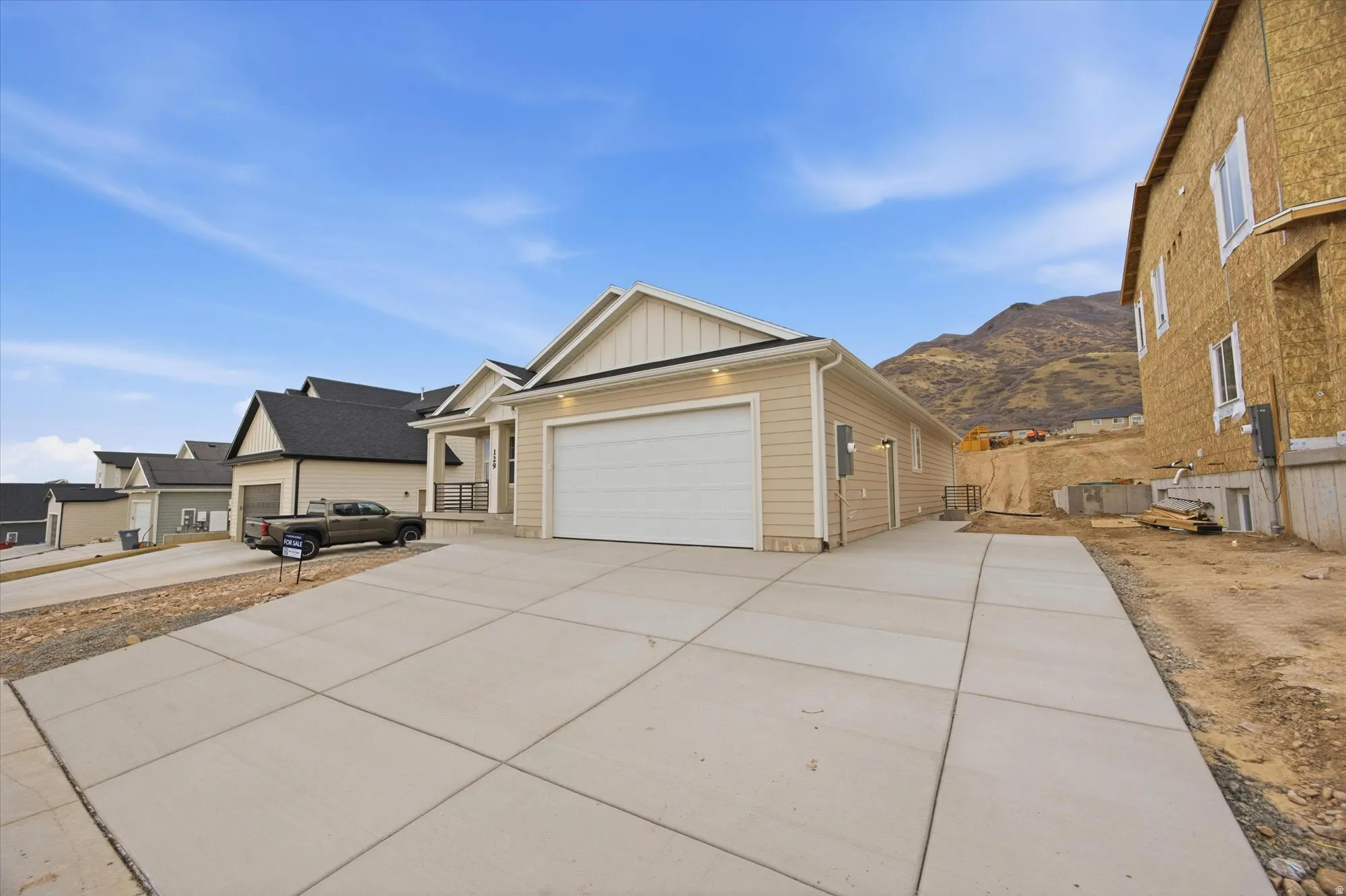 View of front of property featuring board and batten siding, a garage, and driveway